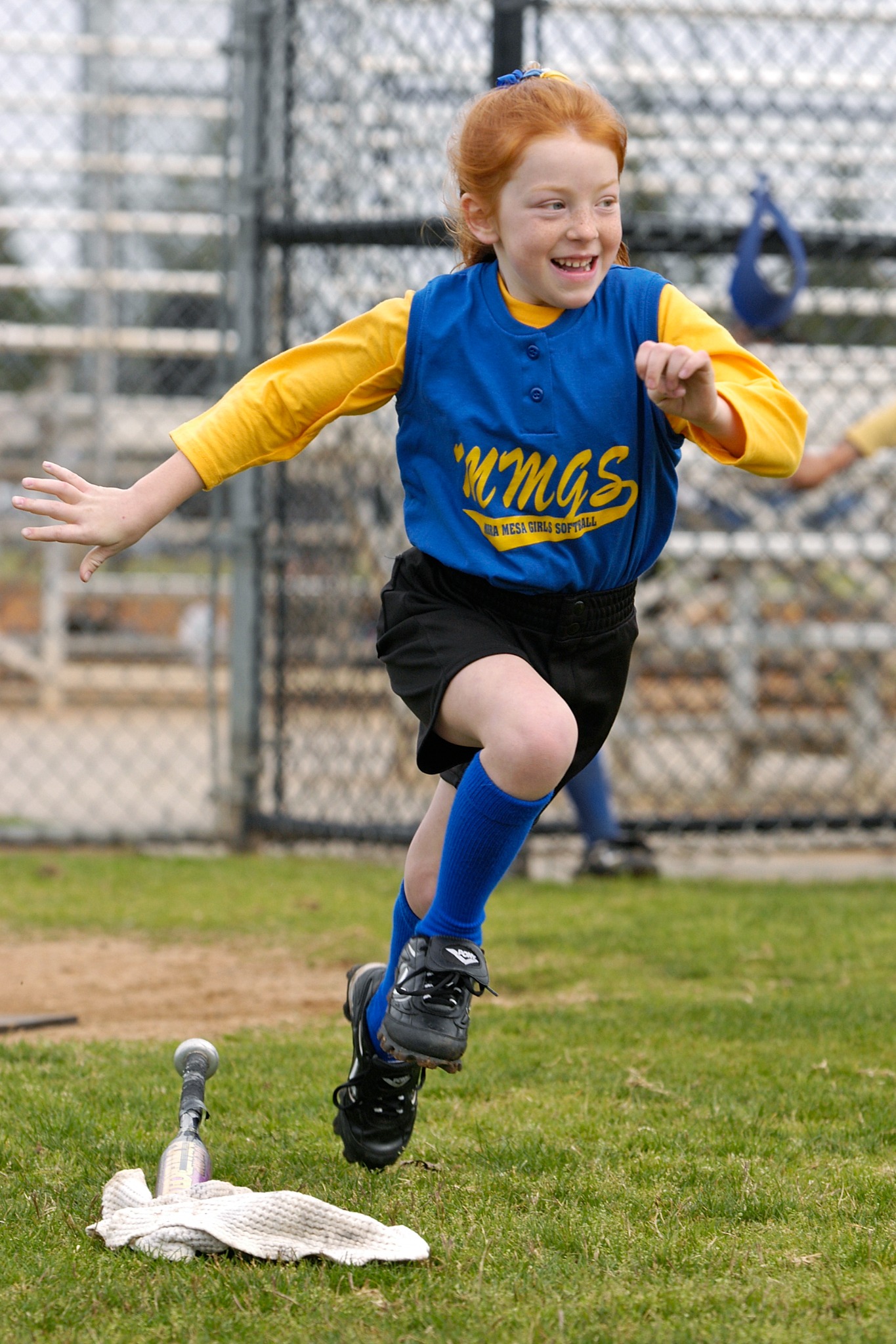Young softball player running the bases with a smile